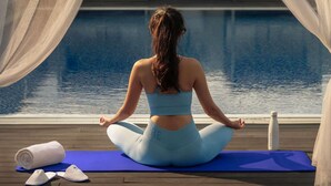 A person meditating on a blue mat by a poolside, with a white towel and slippers beside them. - Novotel Bur Dubai (Dubai)
