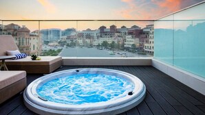 A rooftop terrace with a hot tub, a sofa, and a view of a cityscape. - Novotel Bur Dubai (Dubai)