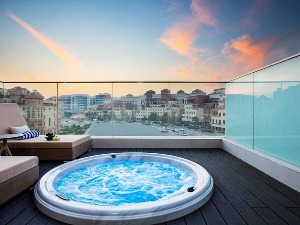 A rooftop terrace with a hot tub, a sofa, and a view of a cityscape. - Novotel Bur Dubai (Dubai)