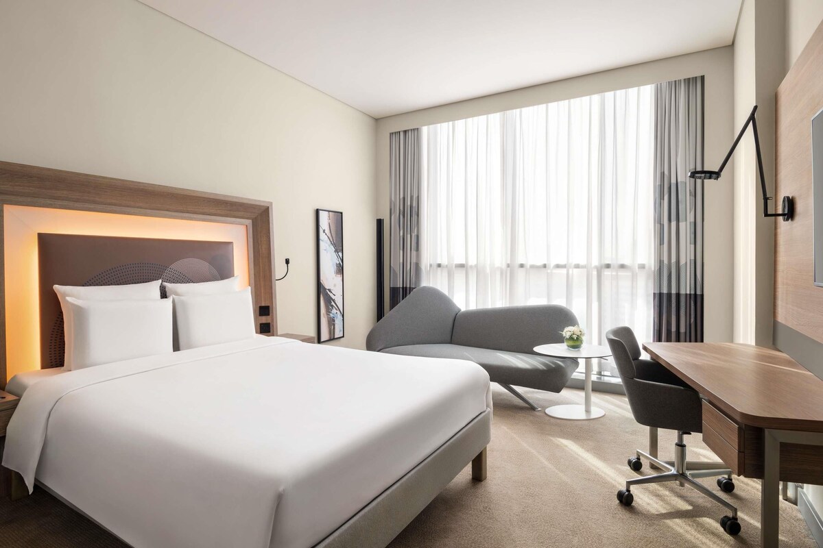 Una habitación de hotel con una cama grande, un escritorio, una silla y un sofá.