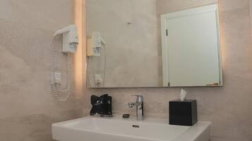 Een badkamer met een witte wastafel, een haardroger, een spiegel en een deur.