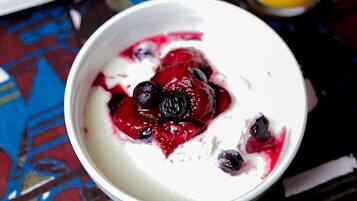 Un tazón de yogur con arándanos y compota de frutos rojos.