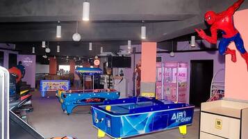 An indoor recreational area with pool tables, arcade games, and a large Spider-Man decoration.
