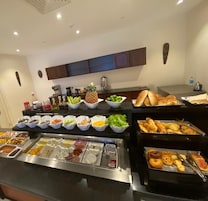 Un bufé con diversos alimentos, entre ellos frutas, verduras y productos horneados.