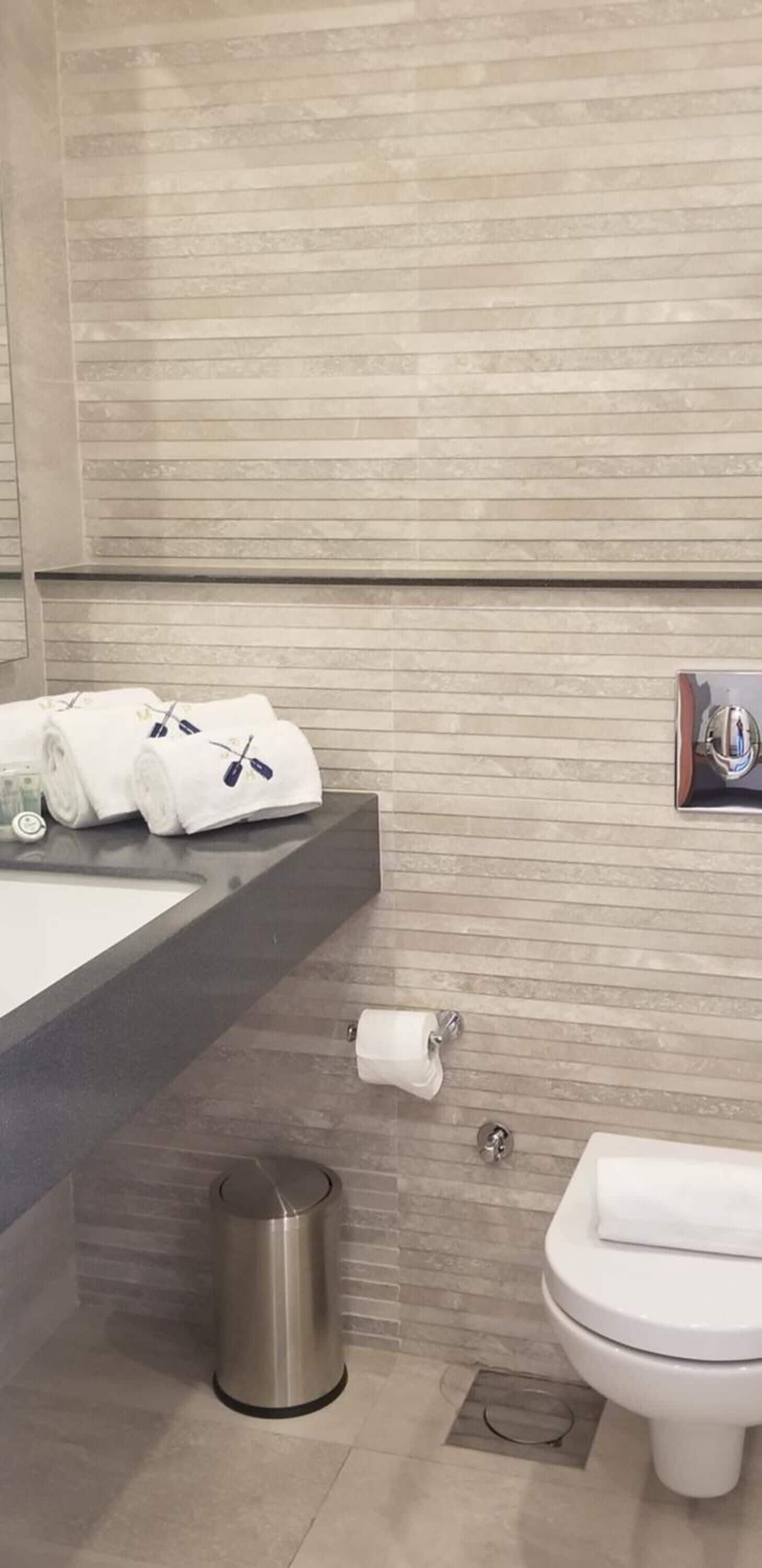 Un baño moderno con un lavabo grande, un inodoro y un cubo de basura.