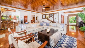 A spacious living area with a large L-shaped sofa, wooden flooring, and a ceiling fan. - Blue Jewel Oceanfront Private Villa (Tamarindo)