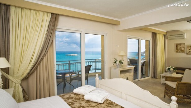 Habitación de hotel con cama, escritorio, silla y vista al océano.