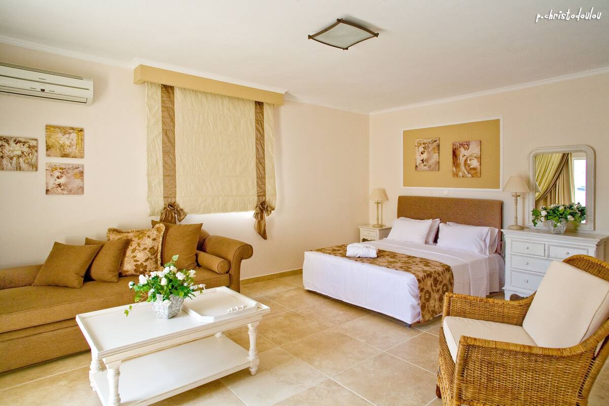 A hotel room with a bed, a sofa, a chair, a coffee table, and a dresser.