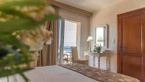 Habitación de hotel con cama, escritorio con lámpara, espejo y puerta.