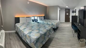 A hotel room with two beds, a desk, a TV, and a radiator.