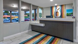 Un espace d’accueil avec un grand panneau portant le chiffre « 6 », un comptoir et de grandes fenêtres donnant sur un parking.