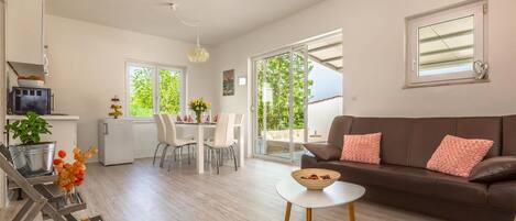 Un salon moderne avec un canapé marron, une table blanche et un coin repas avec des chaises.