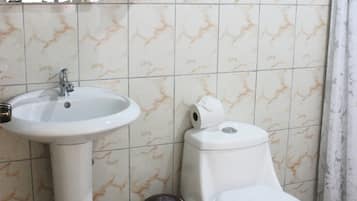 Un baño con lavamanos, inodoro y cubo de basura.