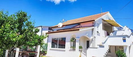 A white building with a tiled roof, a balcony, and a gate.
