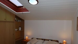Una camera da letto con un letto, due comodini con lampade, un armadio in legno e un lucernario.