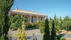 Une maison avec un toit en tuiles, une véranda et une allée gravillonnée.