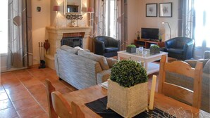 Un salon avec une cheminée, deux canapés, une table basse et un téléviseur.