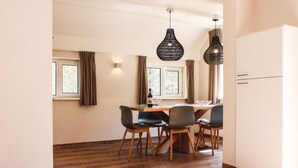 A modern kitchen with wooden flooring, a dining table with four chairs, and two hanging pendant lights. - Awesome home in Ommen with sauna (Ommen)