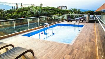 Relax by the pool, surrounded by lush greenery and distant mountains.