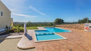 Une piscine divisée en deux zones, entourée d’une terrasse dallée et d’un mur en pierre.