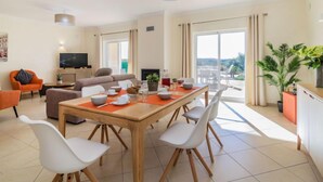 Un salon moderne comprenant un coin repas, un téléviseur à écran plat et un balcon avec vue.