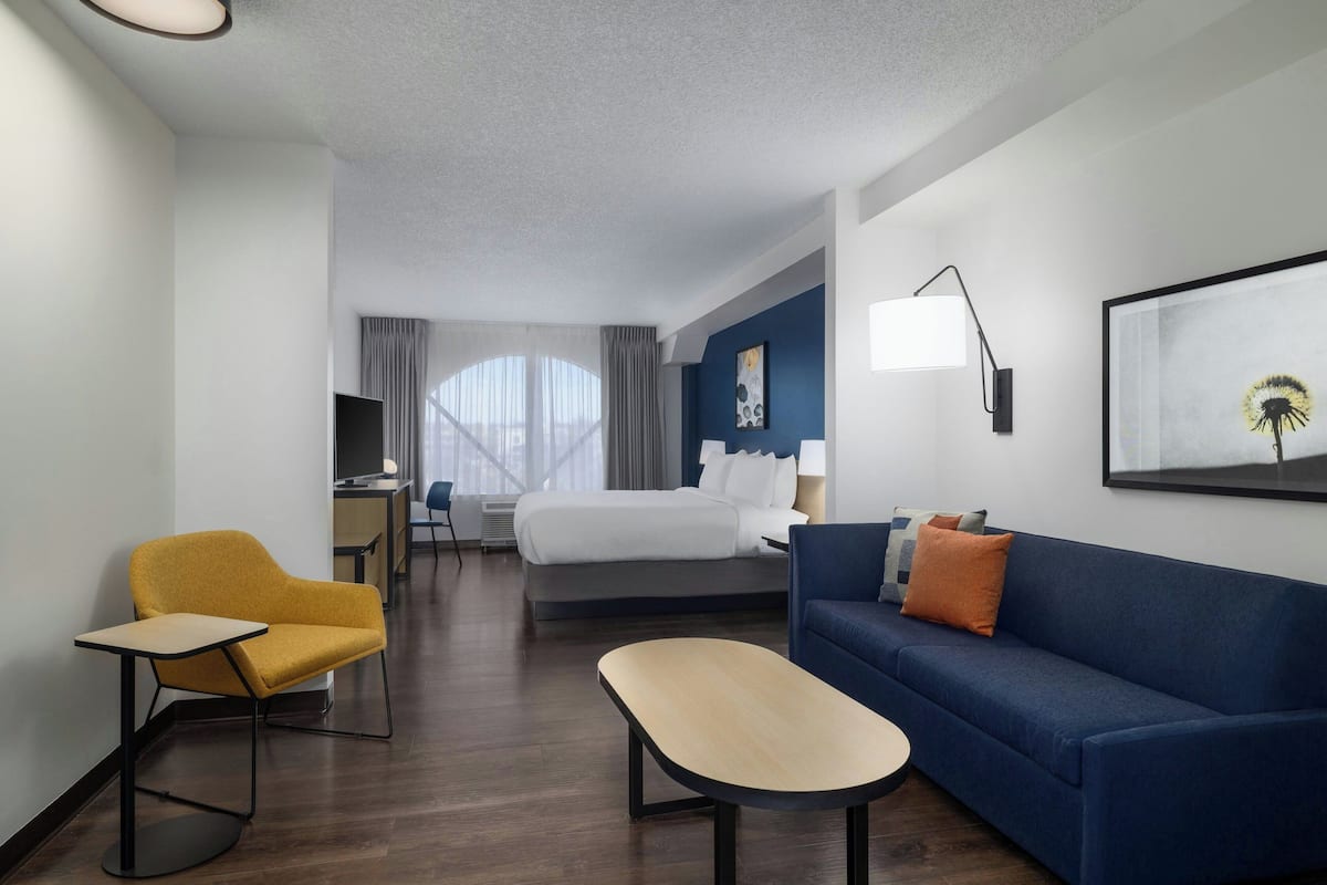 A hotel room with a bed, a sofa, a desk, and a chair.