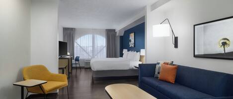 Une chambre d’hôtel avec un lit, un canapé, un bureau et une chaise.