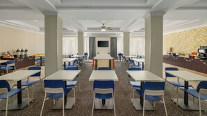 A conference room with tables and chairs, a television, and a kitchen area. - City Express by Marriott Washington, DC Northeast (Washington)