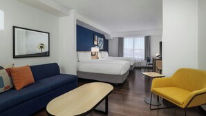A hotel room with a blue sofa, a yellow armchair, a bed, a desk, and a TV. - City Express by Marriott Washington, DC Northeast (Washington)