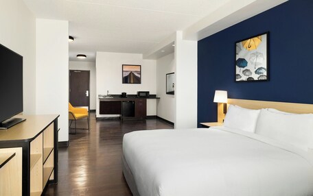 A hotel room with a bed, a desk, a chair, and a television.