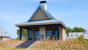 Ett modernt hus med ett sluttande tak, en inglasad veranda och en trappa som leder upp till entrén.