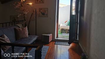 Una habitación acogedora con techo de madera, un sofá, una cama y una puerta que da al exterior.