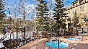 A pool area with two hot tubs, surrounded by a brick patio and a metal fence. - Premier 2 Bedroom Mountain View Condo Located in Historic Downtown Breckenridge Walking Distance to Peak 9 (Breckenridge)