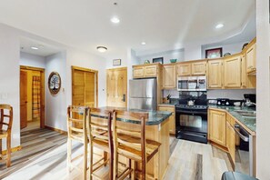 A kitchen with wooden cabinets, a stainless steel refrigerator, and a granite countertop.