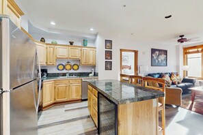 Una cocina amplia con gabinetes de madera, encimera de granito y refrigerador.