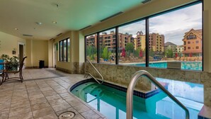 A hotel indoor pool with a view of surrounding buildings.