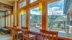 A wooden dining area with large windows overlooking a mountainous landscape. - 2 Bedroom Colorado Mountain Vacation Rental in River Run Village With Hot Tub Access and Walking Distance to Ski (Keystone)
