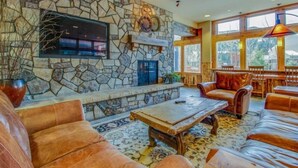A stone fireplace, leather sofas, and a large window with a view. - 2 Bedroom Colorado Mountain Vacation Rental in River Run Village With Hot Tub Access and Walking Distance to Ski (Keystone)