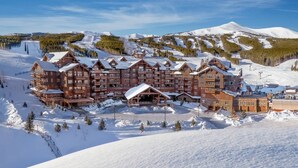 Een ruim landhuis met meerdere gebouwen, skipistes op de achtergrond en een besneeuwd landschap.