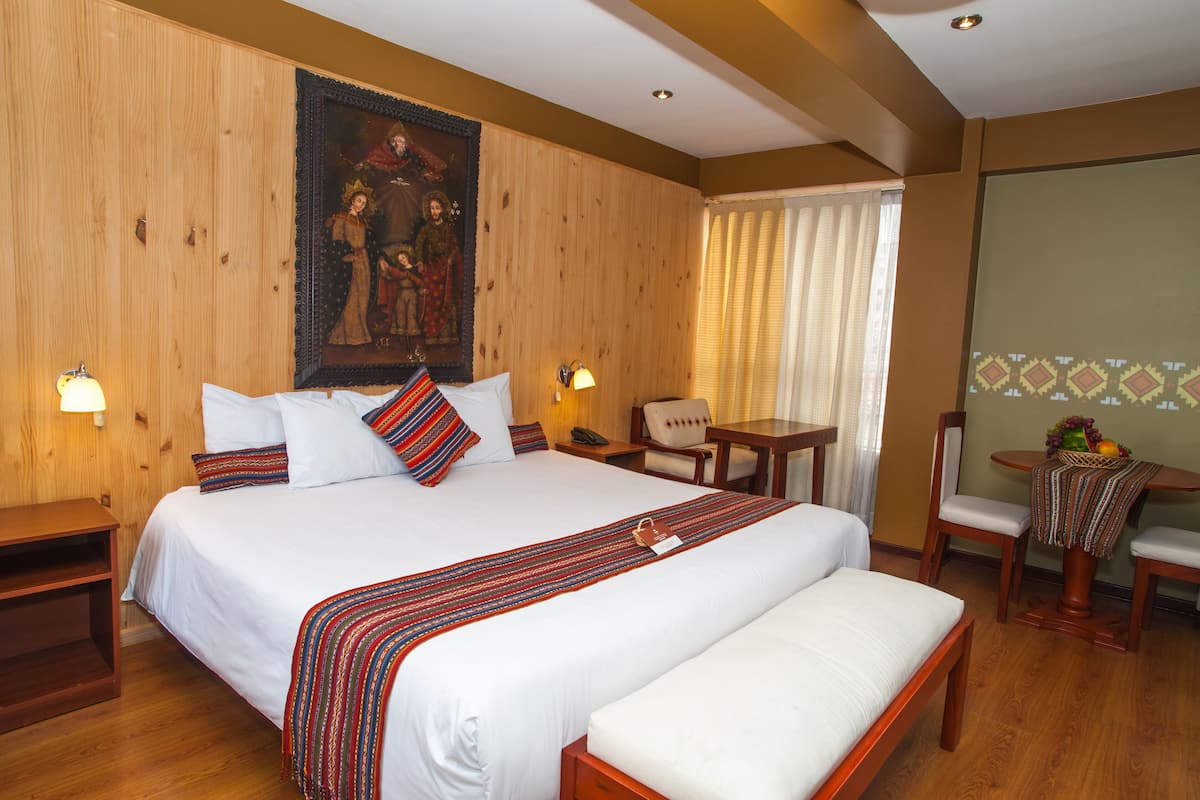 Ein Hotelzimmer mit einem großen Bett, Nachttischen, einem Schreibtisch und einem Sessel.