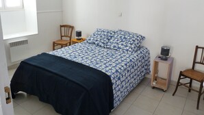 A bedroom with a bed, two chairs, a nightstand, and a window. - apartment of the callade (Peyriac-de-Mer)