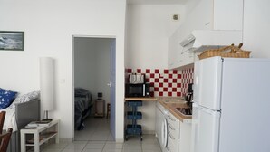 A compact kitchen with a microwave, a refrigerator, and a washing machine. There is a small dining area with a table and chairs. - apartment of the callade (Peyriac-de-Mer)