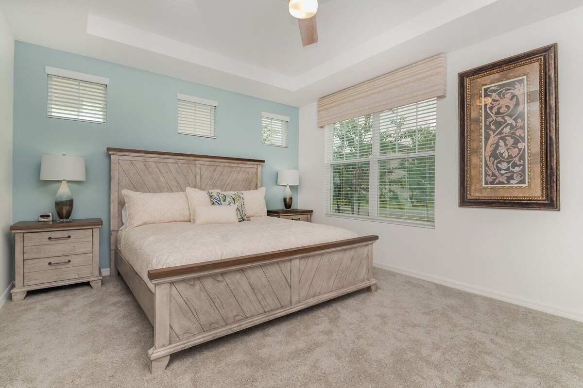A bedroom with a bed, two nightstands, a ceiling fan, and a window with blinds.