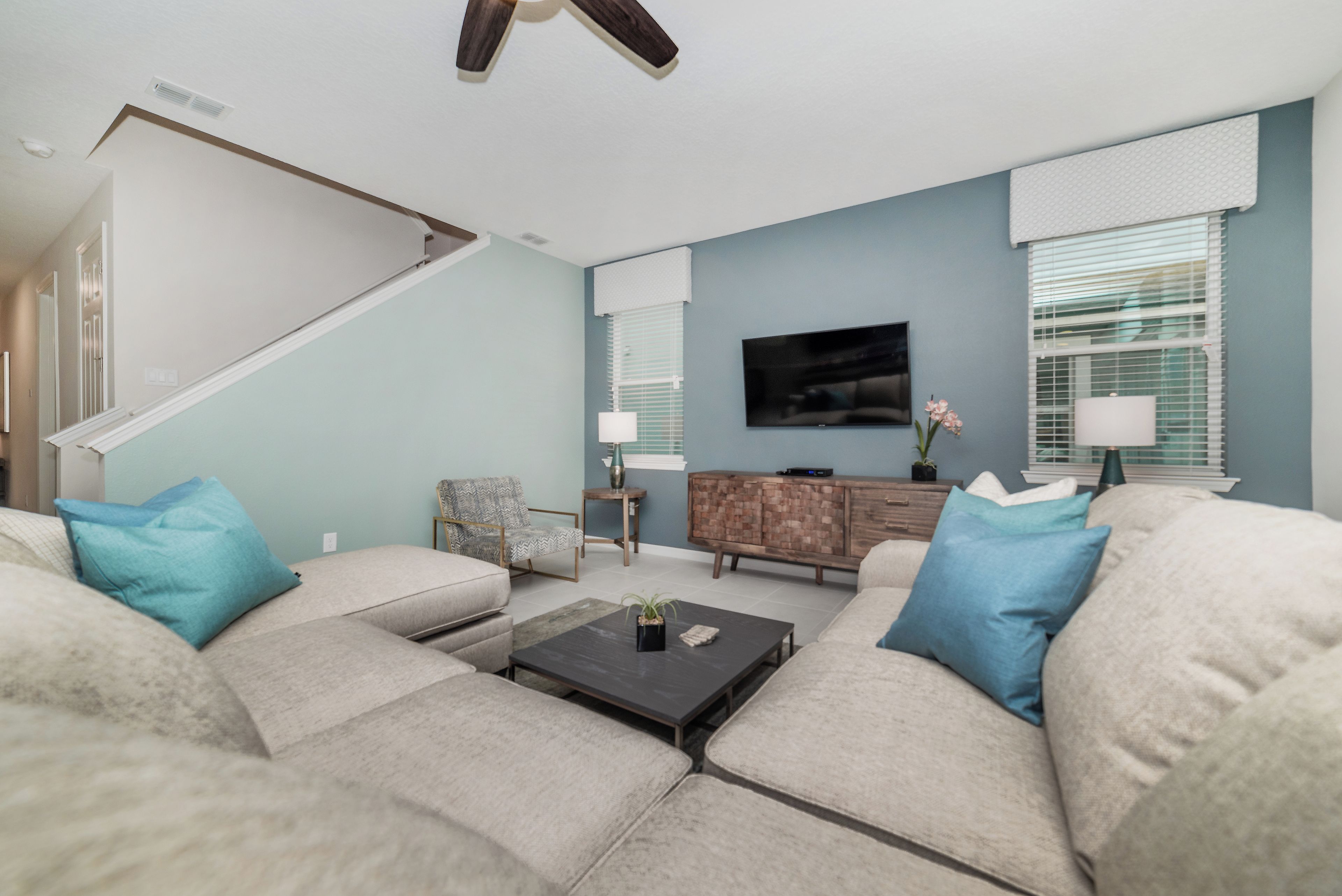 A living room with a sofa set, a coffee table, a TV, and a staircase.