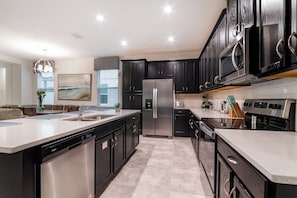 A modern kitchen with dark cabinetry, stainless steel appliances, and a central island.