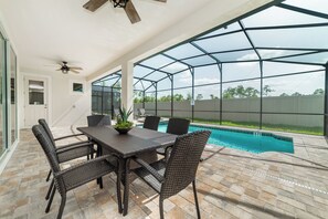 An outdoor patio with a pool, wicker furniture, and a ceiling fan. - Solara Resort Homes and Townhomes (Kissimmee)