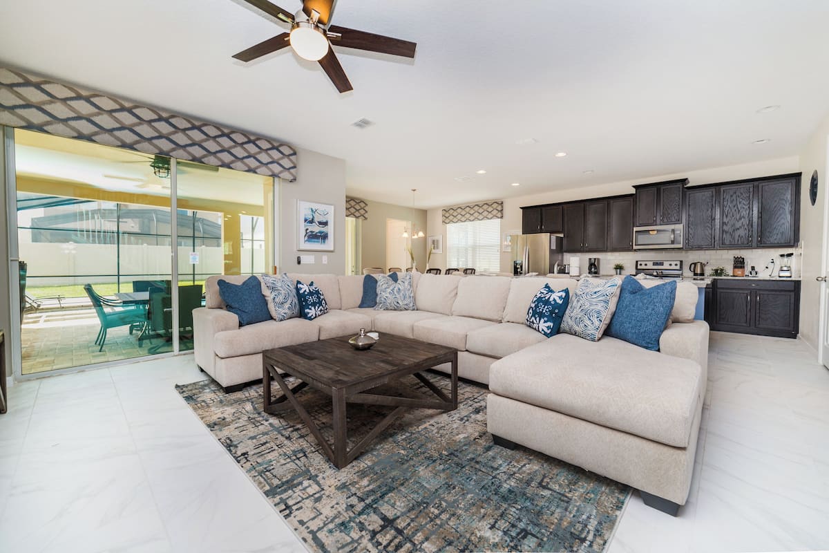 A modern living room with a sectional sofa, a coffee table, and a ceiling fan.