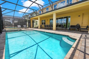 Piscina interior com teto de vidro, espreguiçadeiras e área de estar ao ar livre.