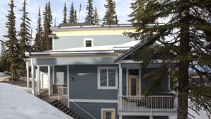 A two-story house with a front porch, a garage, and a staircase leading to the entrance.