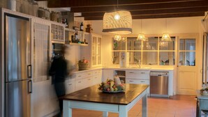 A modern kitchen with white cabinetry, stainless steel appliances, and a central island with a fruit bowl. - Coliving AdD LiVitum (Ciutadella de Menorca)